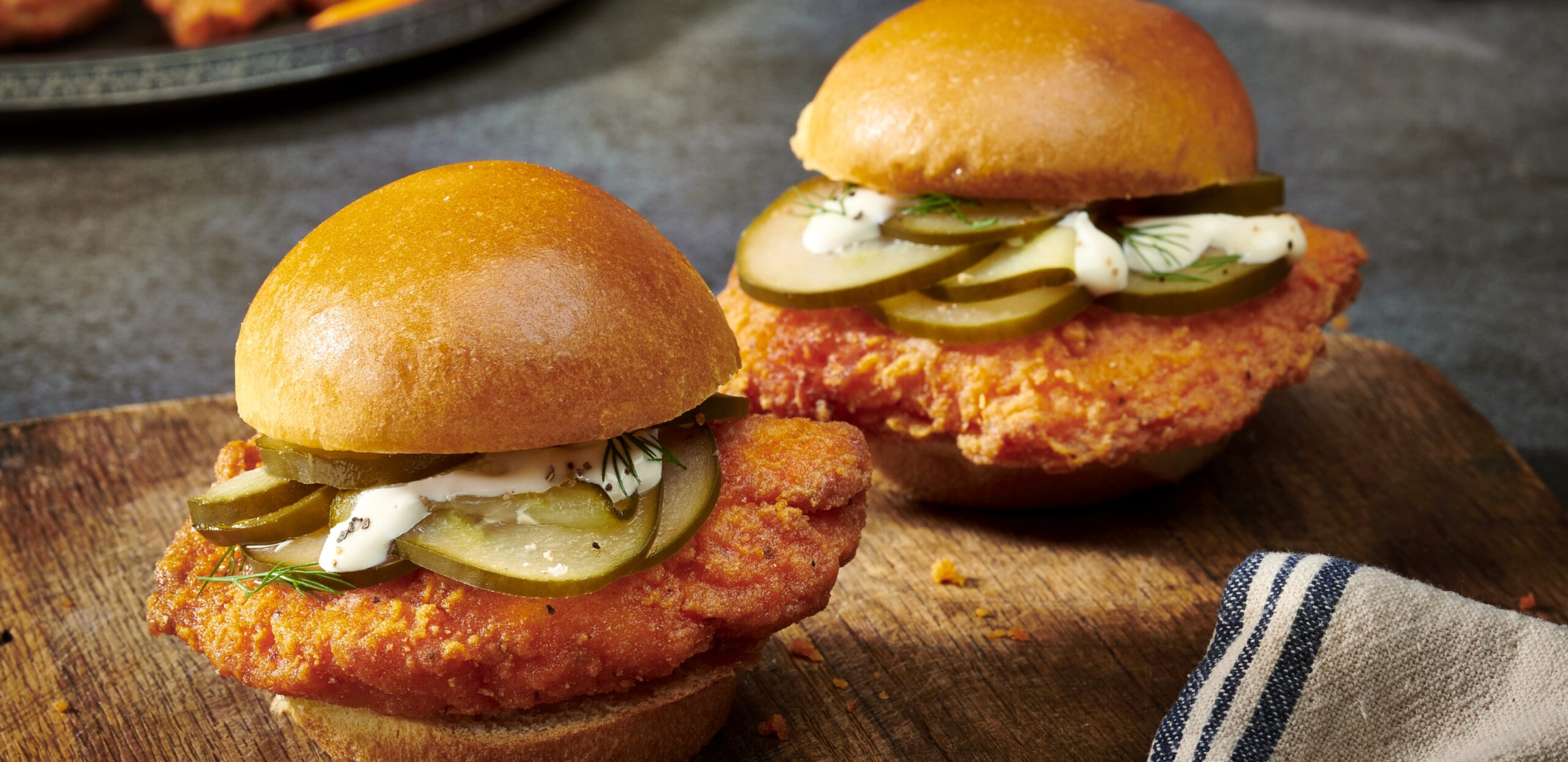 Two chicken sliders on a wood cutting board